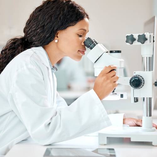 Nothing is too small to see. Shot of a young scientist using a microscope in a lab